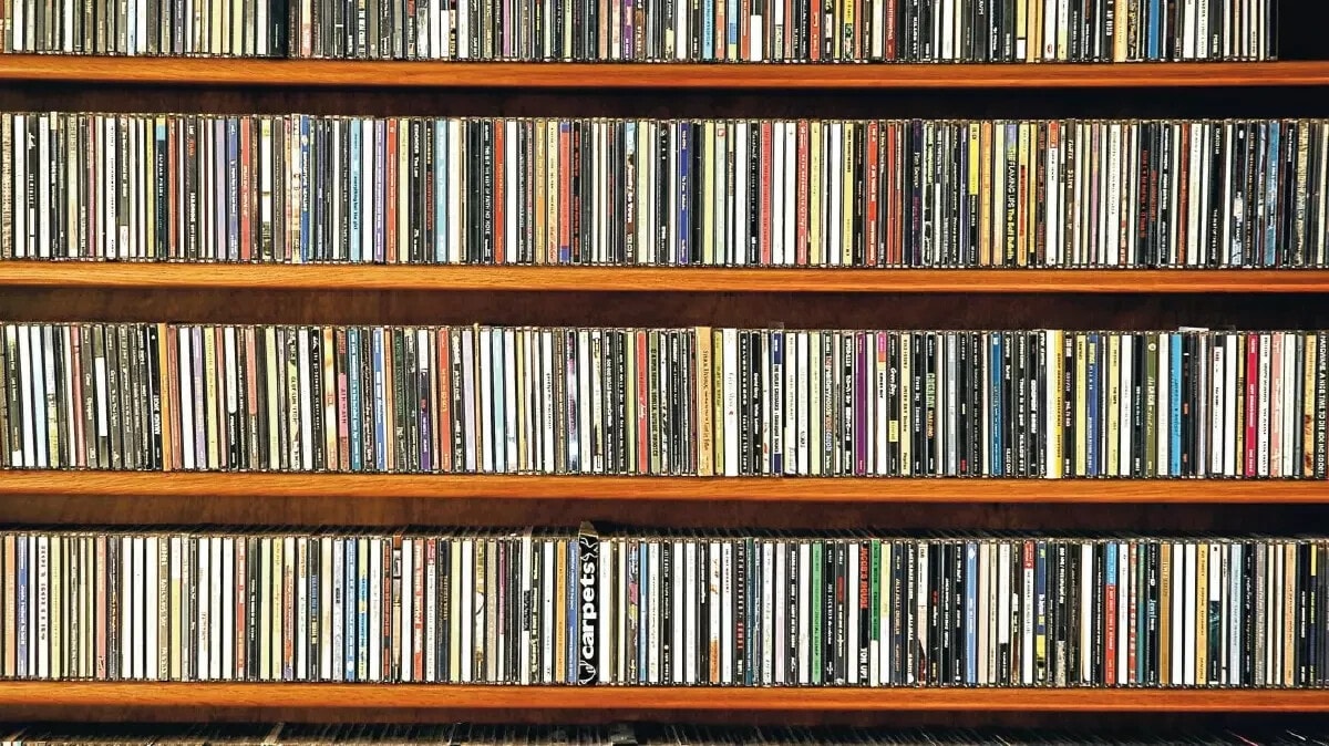Large collection of CDs and DVDs organised on wooden shelves